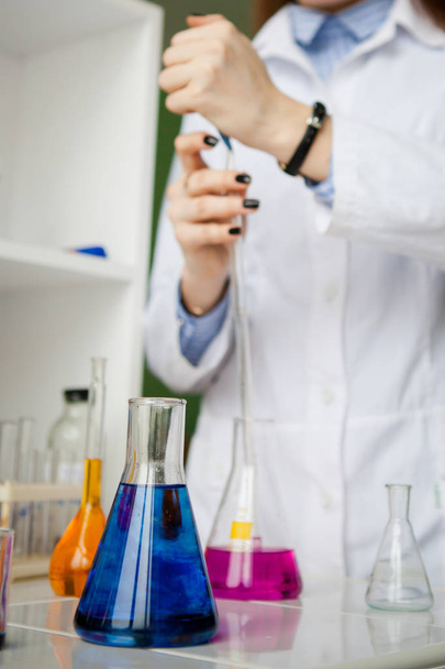 girl lab technician mixes blue and clear liquids in flasks - Fotografie, Obrázek