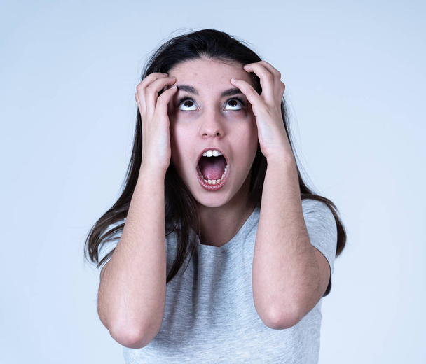 Portrait of young attractive frustrated latin woman with angry and stressed face. Looking mad and crazy shouting and making furious gestures. Facial expressions and emotions and mental health. - Foto, imagen