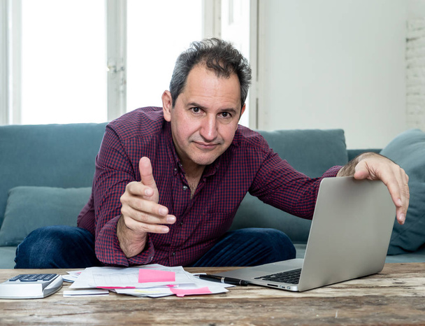 Mature attractive man on computer looking stressed and worried with credit card payments and home finances accounting costs charges taxes and mortgage in paying bills financial problems and debts. - Foto, immagini