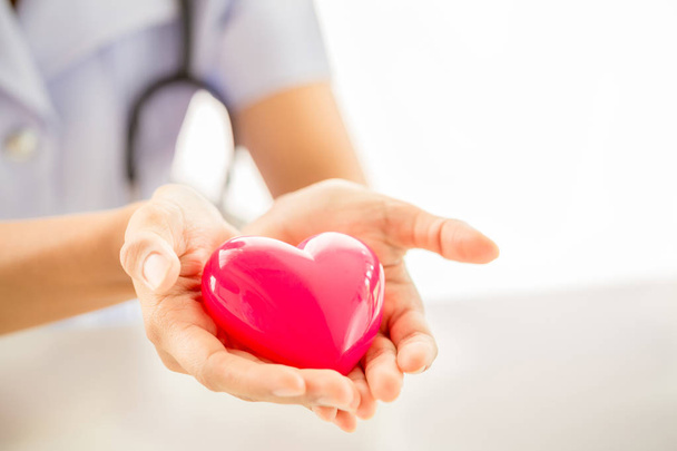Vrouwelijke verpleegster met stethoscoop houden hart - Foto, afbeelding