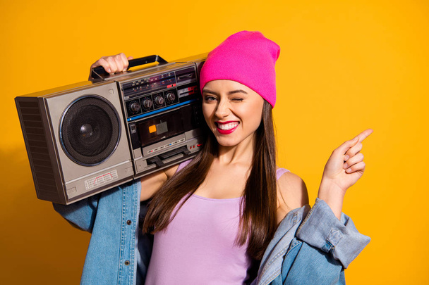 Close up photo funny she her lady hold vintage audio recorder shoulder indicate finger empty space advising buy buyer novelty wear casual jeans denim jacket pink hat isolated yellow vivid background - Foto, Imagem