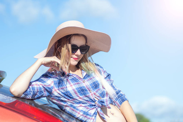 Portrait of romantic beautiful girl in black glasses and big hat. blue sky in background - Foto, Imagen