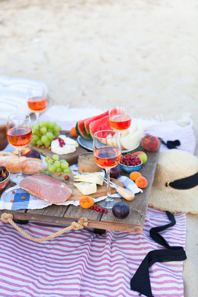 Picnic on the beach at sunset in the style of boho, food and dri - Photo, Image