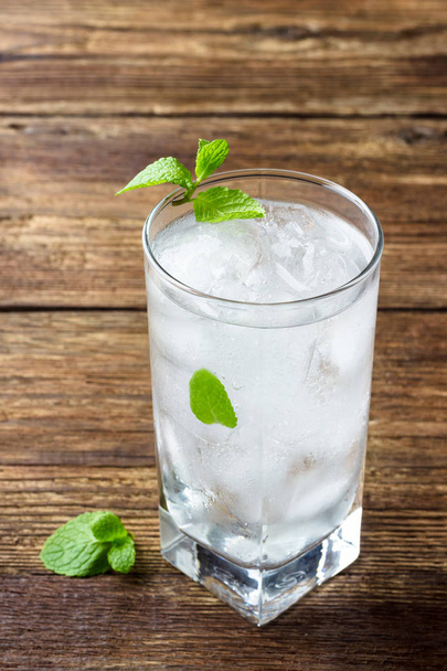 Refreshing beverage with mint and ice in a glass on a wooden table. - Zdjęcie, obraz