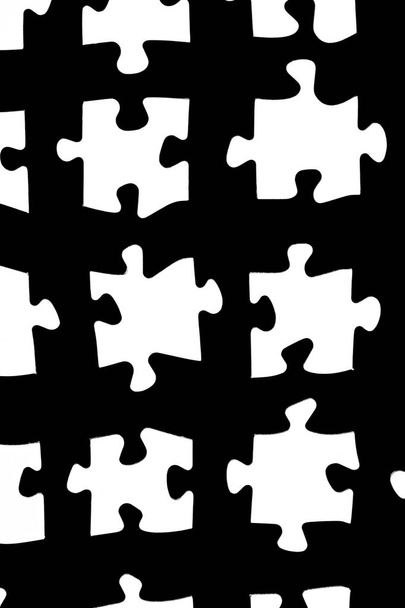 Białe kawałki układanki na czarnym tle z pewnej odległości między poszczególnymi częściami-koncepcja dla sub-Steps lub sub-elementy dużej całości prezentowane z puzzli  - Zdjęcie, obraz