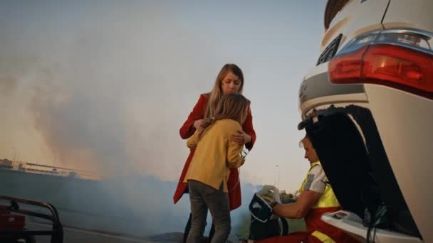 Autounfall: Verletztes junges Mädchen findet wieder zu ihrer liebevollen Mutter, Sanitäter gibt Sauerstoffmaske Im Hintergrund Überschlagwagen und mutige Feuerwehrleute retten Leben - Filmmaterial, Video