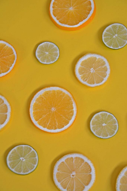 citrus fruits like orange, lime and lemons on a monochrome background - sliced lemons, limes and oranges with a colored background - Photo, Image