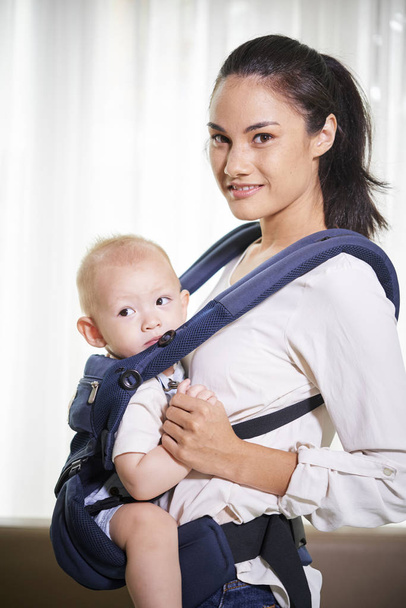Portrait de jeune femme souriante métissée portant un petit fils en fronde
 - Photo, image