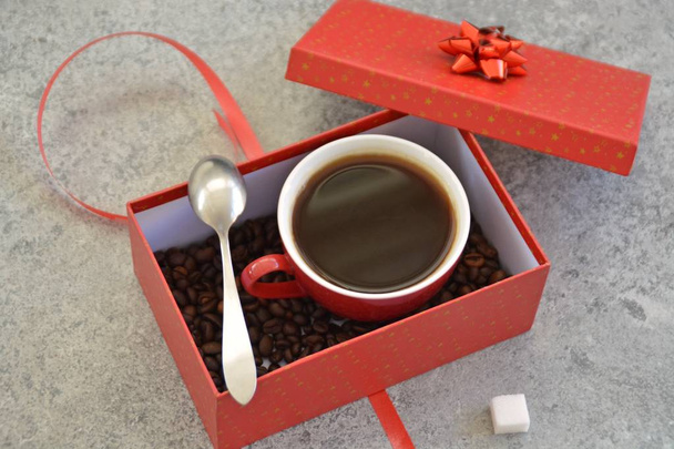 Filiżanka pełna kawy jest w pudełku na prezent świąteczny z ziaren kawy w nim-Kawa jako smakołyku i prezent na Boże Narodzenie ładnie zapakowane  - Zdjęcie, obraz