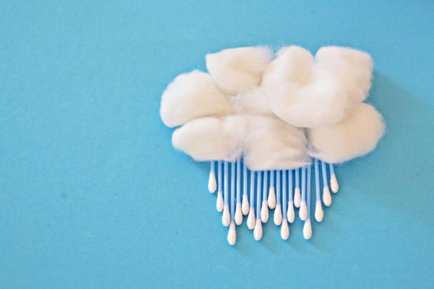 Bola de algodão como uma lã e auriculares como chuva ou neve em um fundo azul conceito para chuva ou rápido com cotonetes e bolas de algodão
 - Foto, Imagem