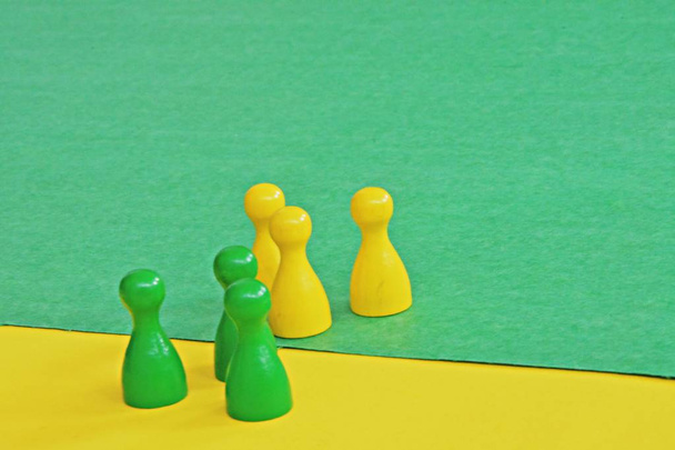equipo de personajes de juego de madera de un juego de mesa se enfrentan entre sí y son recibidos por el respectivo fondo de color opuesto
  - Foto, Imagen