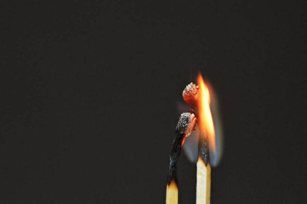 zwei verbrannte Streichhölzer vor schwarzem Hintergrund sehen aus wie ein Paar, das kuschelt und intim miteinander ist - Konzept symbolisiert feurige Liebe - Foto, Bild