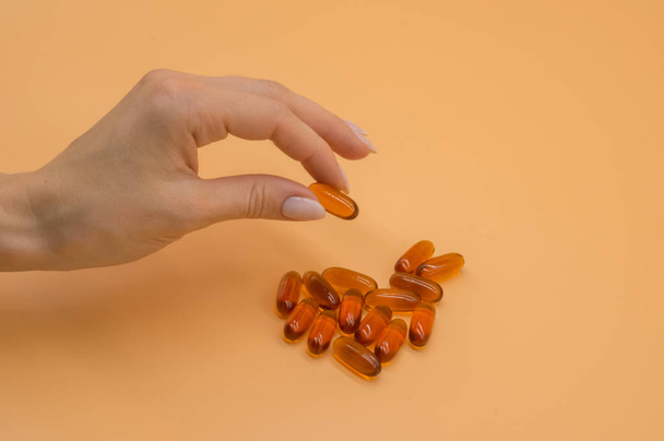 Beautiful hands with bunch of vitamins on orange background - Fotoğraf, Görsel