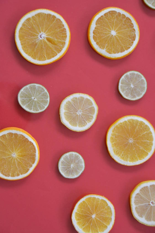 turuncu, limon ve limon gibi narenciye, tek renkli arka planda dilimlenmiş limon, Limes ve portakal renkli bir arka plan - Fotoğraf, Görsel