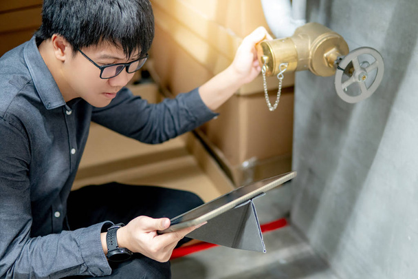 Técnico asiático revisando válvula de compuerta de agua
 - Foto, imagen