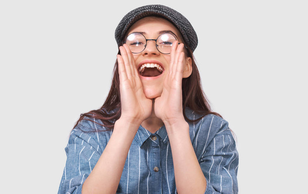 Horizontal portrait of emotive happy lady exclaims loudly with optimism, wears blue shirt, isolated over studio background. Student girl enjoys life, feels overjoyed. People, excitement, joy concept - Foto, immagini