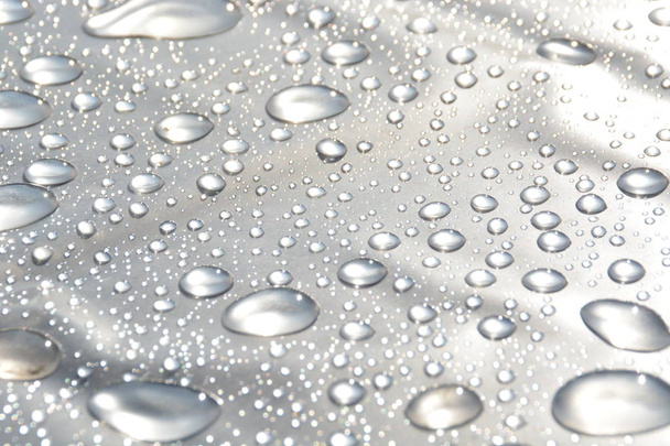 Des gouttes d'eau s'accumulent sur une pellicule plastique après une pluie et réfléchissent le soleil qui brille après la pluie - un jeu naturel avec la lumière, les gouttes de pluie et le soleil
 - Photo, image