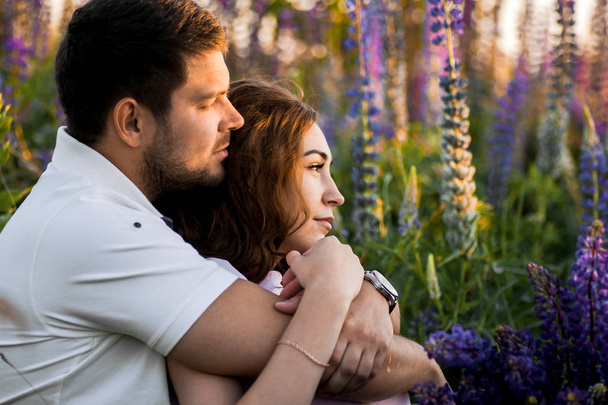Portrait of couple in love relaxing in field of lupines - Photo, Image