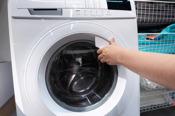 Close-up da mão da mulher ao abrir uma porta da máquina de lavar roupa, conceito de estilo de vida de limpeza
 - Foto, Imagem