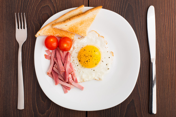 Fried egg with toasts, ham and cherry tomato - Foto, afbeelding