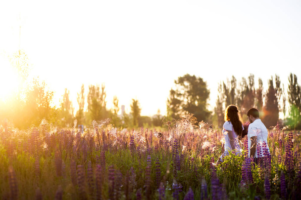 Happy romantic couple walking holding hands in field of lupines - Photo, Image