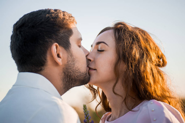 романтическая пара с букетом люпин, целующихся в поле
 - Фото, изображение