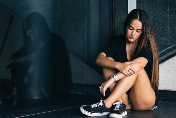 самотня і сумна дівчина сидить на підлозі
 - Фото, зображення