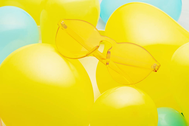 Widok z góry modne okulary przeciwsłoneczne na tle pastelowych wykonanych z żółtych i niebieskich balonów - Zdjęcie, obraz