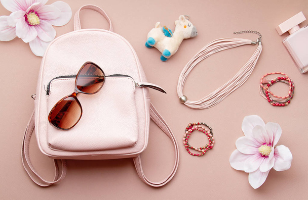 Acostado plano con accesorios de mujer rosa con mochila y mano de mujer sosteniendo las gafas de sol. Tendencias de moda de verano, concepto de compras
 - Foto, imagen