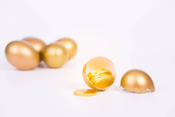 zlaté vajíčko a zlatá mince na bílém pozadí - Fotografie, Obrázek