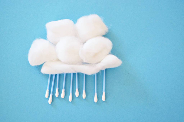 Cotton ball as a wool and earsticks as rain or snow on a blue background - concept for rain or fast with cotton swabs and cotton balls - Fotografie, Obrázek