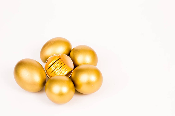 Gold-Ei und Goldmünze auf weißem Hintergrund, Wohlstandskonzept - Foto, Bild