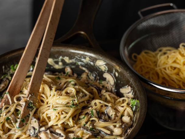 Close view of pasta mixing with mushroom sauce and parmesan cheese in pan - Foto, imagen