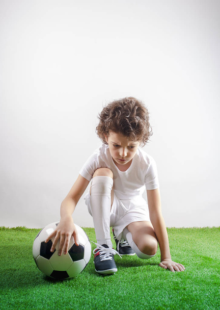 Disappointed little footballer sitting on the grass. Copy space - Foto, immagini