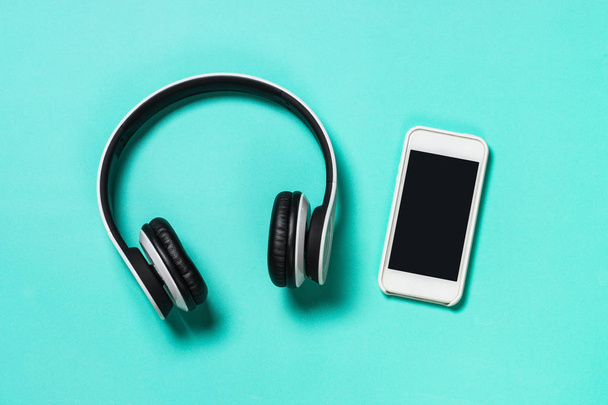 Headphones and smartphone on blue. - Zdjęcie, obraz