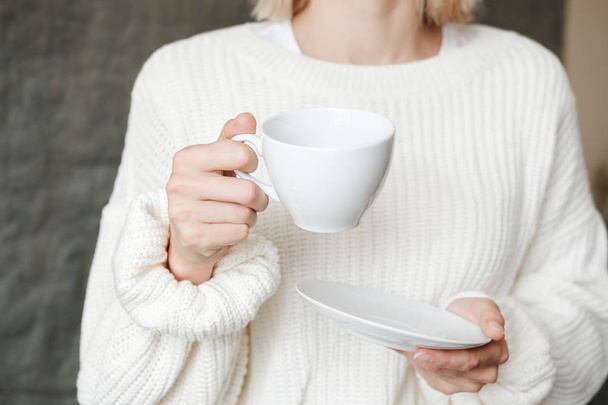 Femme en pull tricoté blanc tenant une tasse de café. Mains féminines avec une tasse de thé. Gros plan
 - Photo, image