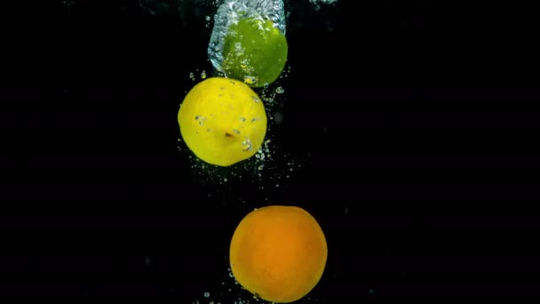 Tropical yellow lemons and green limes fall into crystal clear water. - Filmati, video