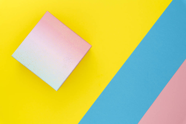 Geschenkbox auf pastellfarbenem, trendy geometrischem Hintergrund. Geburtstagsfeier präsentiert Konzept mit Kopierraum. Ansicht von oben. flache Lage - Foto, Bild