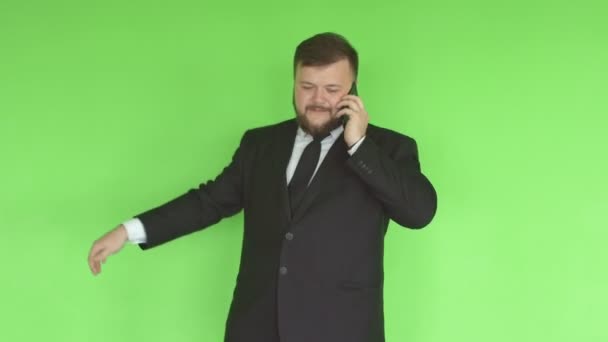 Young caucasian male businessman with a beard and in a suit twirling a hoop in the gym and talking on the phone against a green wall, healthy lifestyle - Felvétel, videó