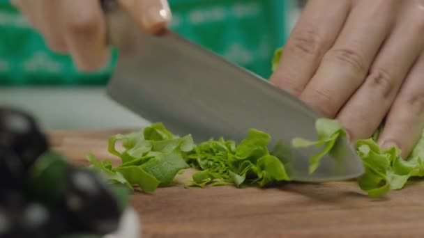 Close-up van de vrouwelijke handen snijden salade bladeren op houten plank  - Video