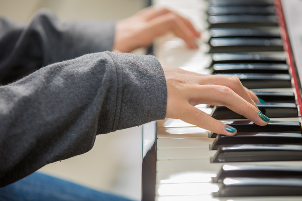 クローズアップ女性の手がピアノを弾く.   - 写真・画像