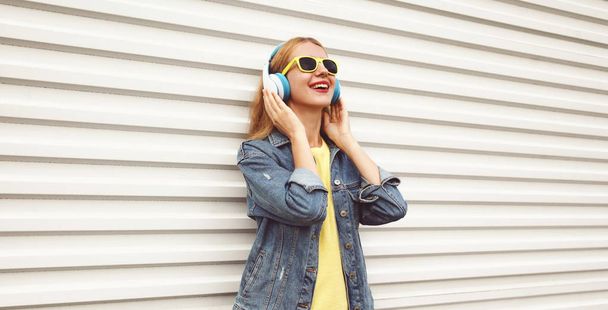 Cool girl in wireless headphones enjoying listening to music on  - Foto, Imagen