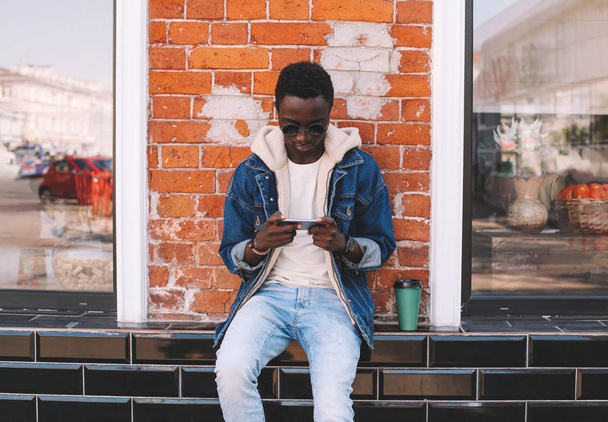 cool urban african man with smartphone, coffee cup sitting on ci - Foto, Imagen