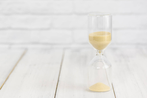 Hourglass on white wood table over white brick background with c - Photo, Image