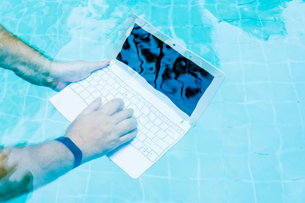 Męskie ręce z laptopem pracujących pod wodą. Koncepcja utrudcji w pracy. Rozmycie streszczenie tło. - Zdjęcie, obraz