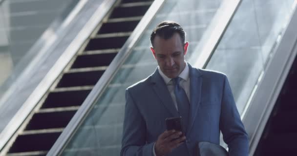 Front view of Caucasian Businessman using mobile phone on escalator in a modern office 4k - Materiał filmowy, wideo