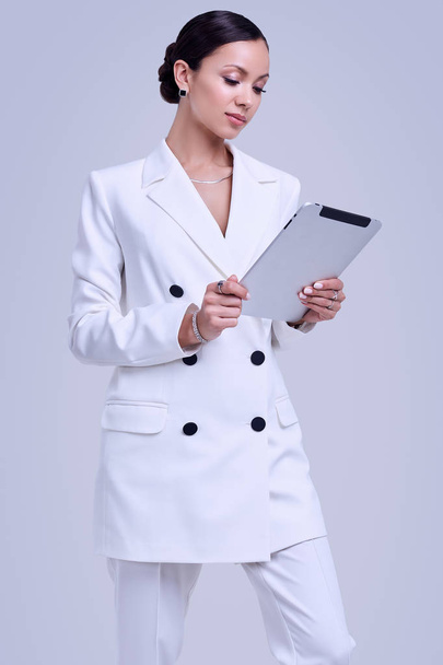Gorgeous latin women in fashion white suit with digital tablet - Foto, afbeelding