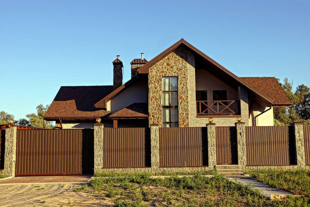 part of a long fence with closed brown iron gates and a large private house - Photo, Image