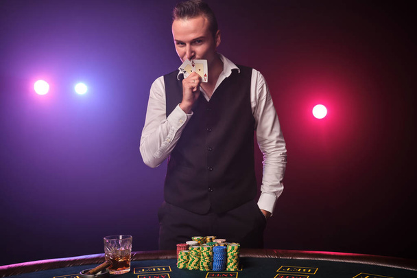 Bohatý člověk hraje poker s nadšením v kasinu na černém pozadí. - Fotografie, Obrázek