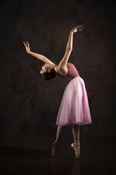 A slender girl in a pink skirt and beige top dancing ballet. - Fotó, kép